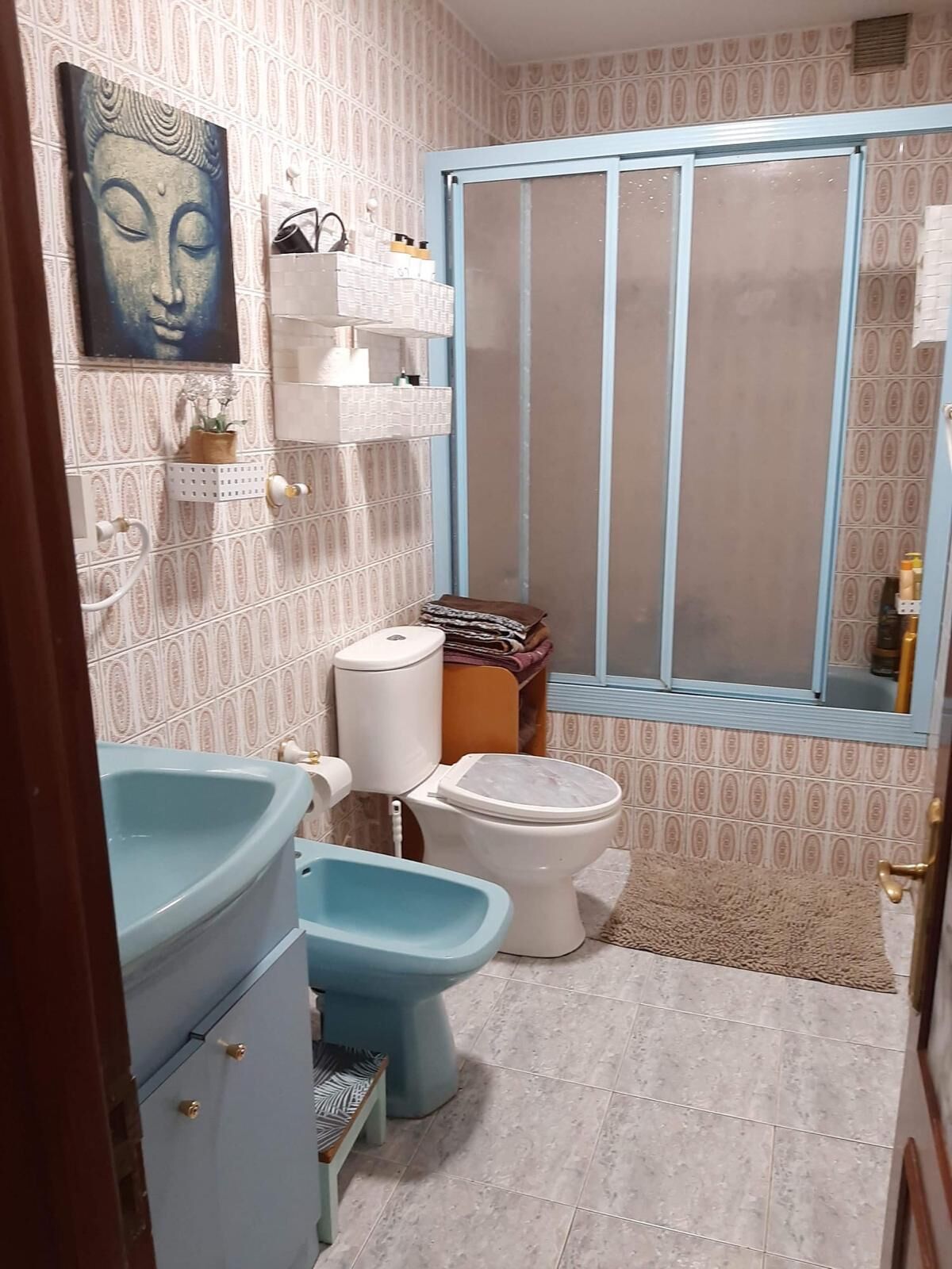 Et badeværelse med toilet, bidet og vask. Der er et vindue med udsigt udad.