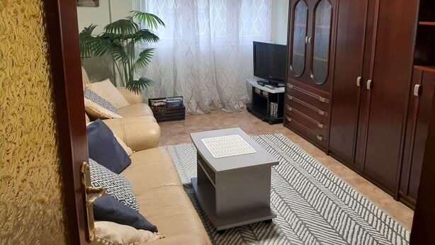 A living room with a sofa, a coffee table, a TV, and wooden cabinets.