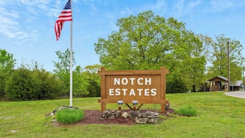 Een houten bord met daarop 'Notch Estates', een Amerikaanse vlag en een klein huisje in de achtergrond.