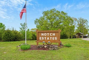 Un panneau en bois sur lequel on peut lire « Notch Estates », un drapeau américain et, au fond, une petite construction qui ressemble à un chalet.
