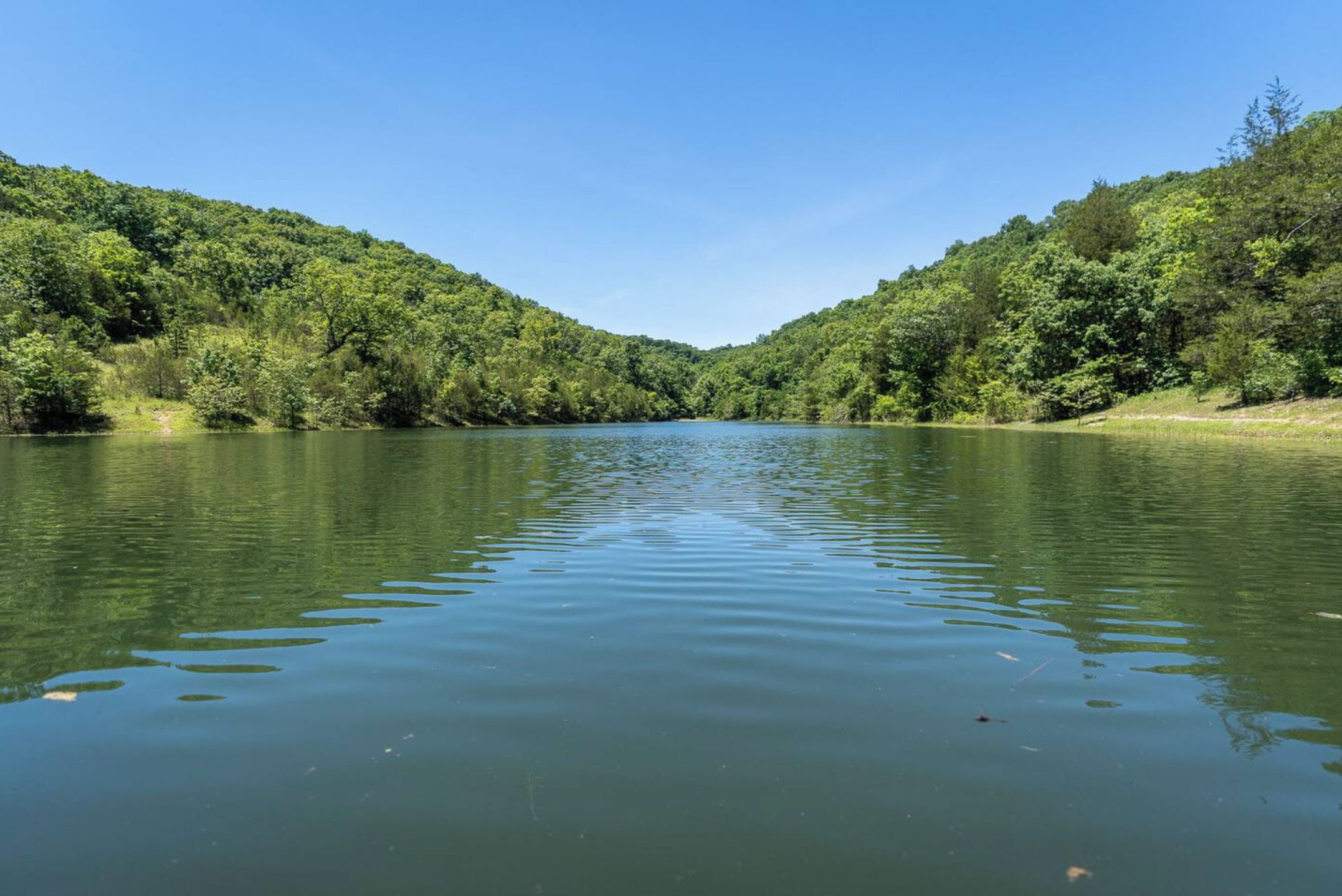 A calm river flanked by lush green hills.