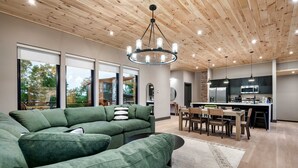 A modern living room with a sectional sofa, a dining area with a table and chairs, and a kitchen with appliances.