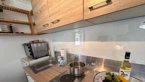 A modern kitchen with wooden cabinets, a stainless steel sink, a built-in stove, and a bowl of fruit on the counter. - Vacation apartment in Eickhof: Relax in nature in the idyllic Warnow region - (Warnow)