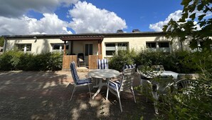 A building with a patio area featuring outdoor seating and a covered entrance. - Vacation apartment in Eickhof: Relax in nature in the idyllic Warnow region - (Warnow)