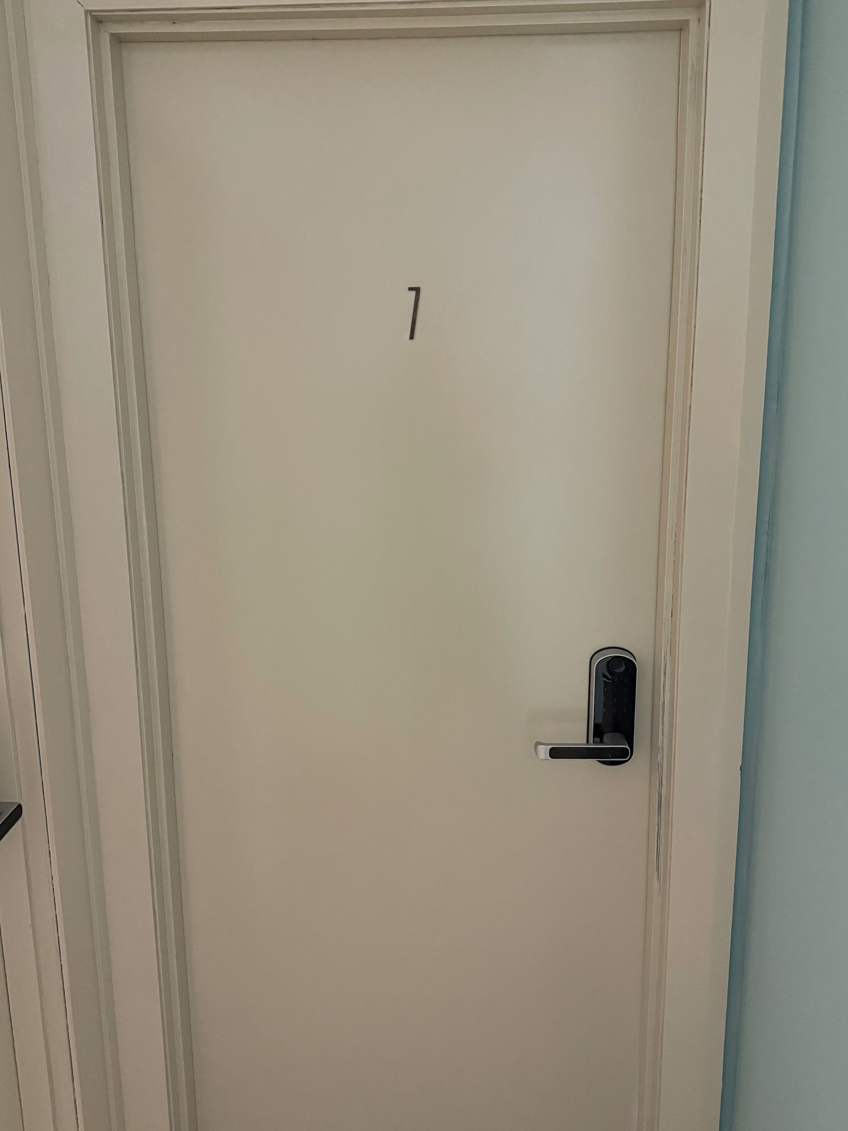 A white door with a number '7' and a modern door handle.