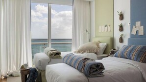 A bedroom with two beds, a view of the sea, and a small table with a plant. - Boavista Apartment (Praia da Vitória)