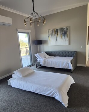 A hotel room with two beds, a large window, and a modern chandelier.