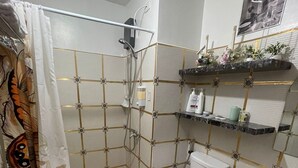 Un baño con ducha, inodoro, lavabo y estantes decorativos.