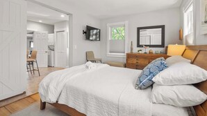 A bedroom with a bed, dresser, and a television on the wall. - Charming Getaway 1 Block from Beach! (Provincetown)