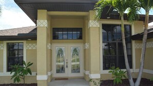A two-story building with a yellow facade, large windows, and a central entrance with glass doors.