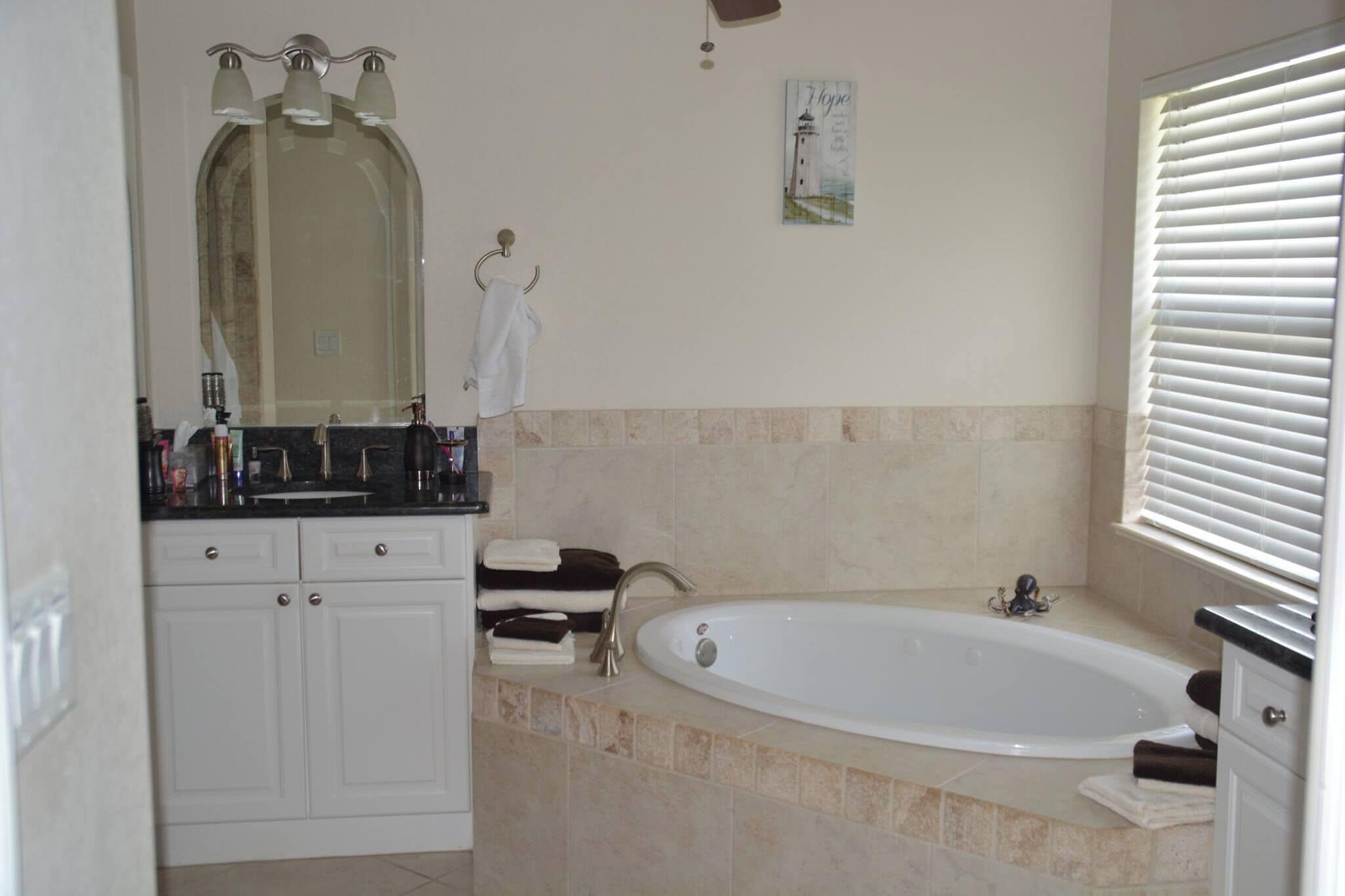 A bathroom with a bathtub, a vanity with a mirror, and a towel rack.