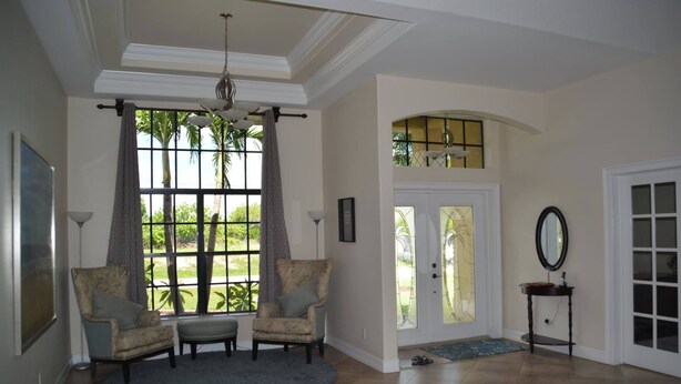 A spacious living room with two armchairs, a coffee table, and a large window with a view of greenery.