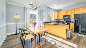 A modern kitchen with wooden cabinets, a black refrigerator, and a central island. - Cozy Corner Oasis (Cornelius)