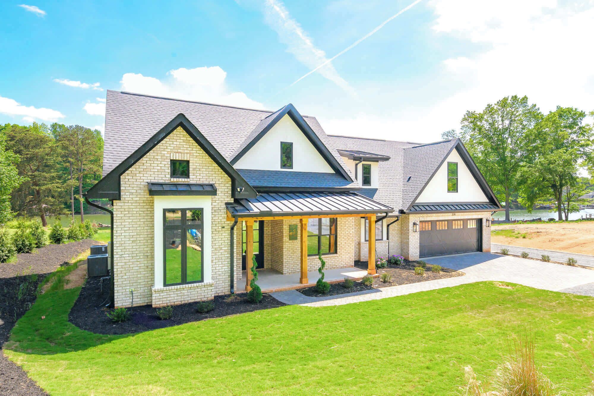 A modern two-story house with a garage, a covered porch, and a well-maintained lawn.