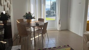 A dining area with a round table, chairs, and potted plants. - Two Bedroom Apartment R C Porto Martins Pools (Porto Martins)