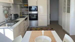 A compact kitchen with white cabinets, a built-in oven, and a coffee maker. - Two Bedroom Apartment R C Porto Martins Pools (Porto Martins)
