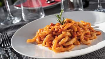 Ein Teller Pasta mit Garnitur auf einem Tisch mit schwarzem Tischtuch.