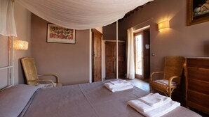 Una habitación de hotel con una cama grande, dos sillones, un aparador de madera y un cuadro en la pared.