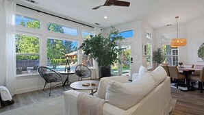 A spacious living room with a large white sofa, a dining area with a table and chairs, and a ceiling fan. - Relaxing 3BAPool+Hot Tub Near the River & Wineries (Walnut Grove)