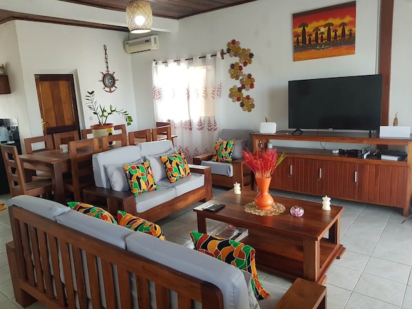 A living room with a sofa, chairs, a coffee table, a TV, and a cabinet.