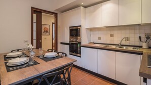A modern kitchen with white cabinets, a stainless steel oven, and a sink. - Joivy Piazza di Spagna apartment (Rome)
