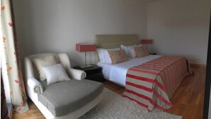 Un dormitorio con cama, una silla, una mesita de noche y una lámpara.