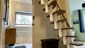 Una escalera de caracol de diseño moderno, un armario de madera y un ventanal con vistas a árboles.