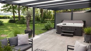 Un área de estar exterior techada con un jacuzzi, un sofá y una mesa de centro.