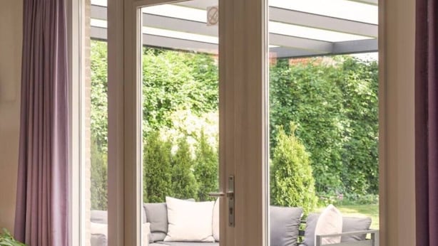 Habitación con puerta de vidrio corrediza que da a una zona exterior con sala y mesa.