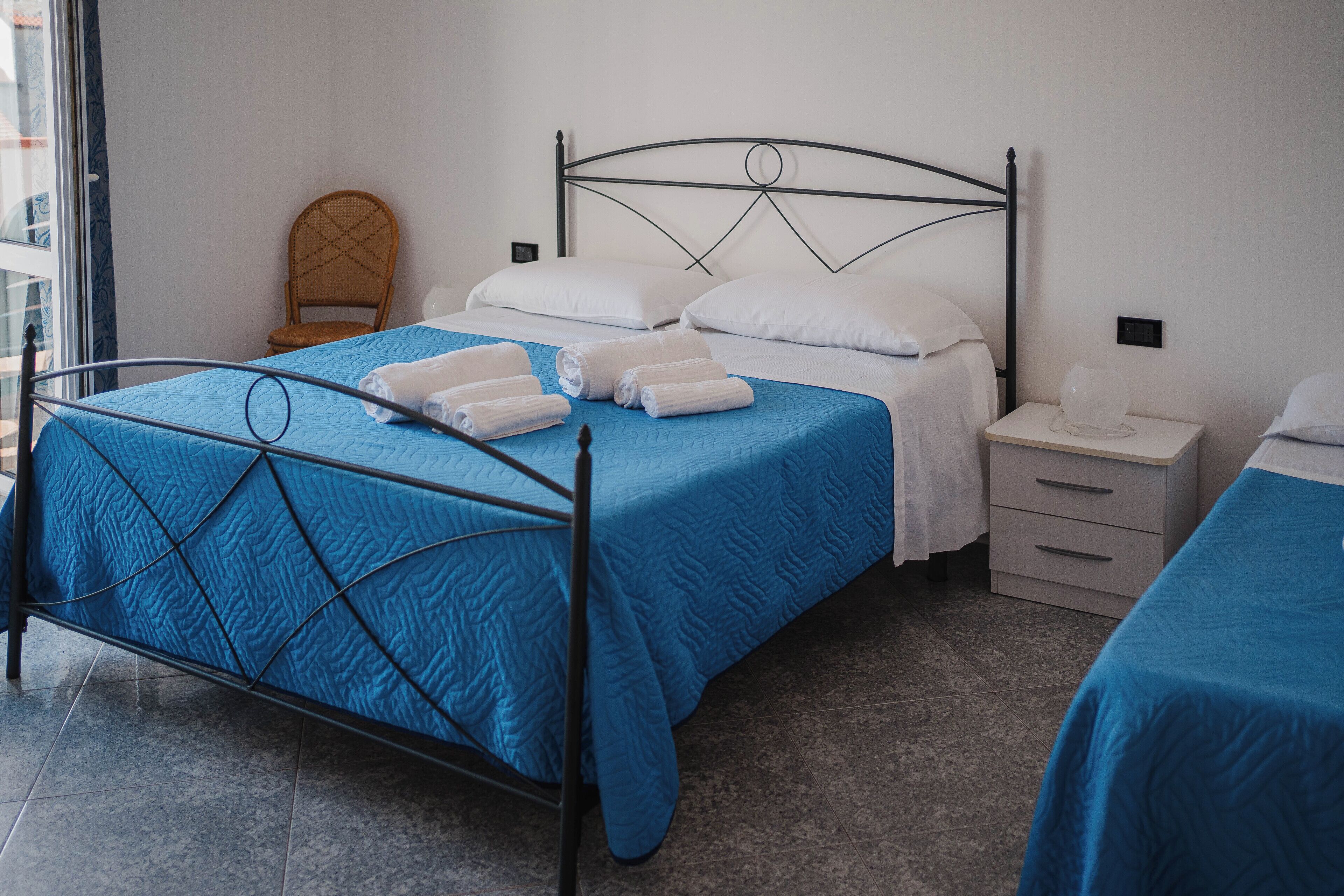 Une chambre d’hôtel avec un lit, une table de chevet, une chaise et une fenêtre.