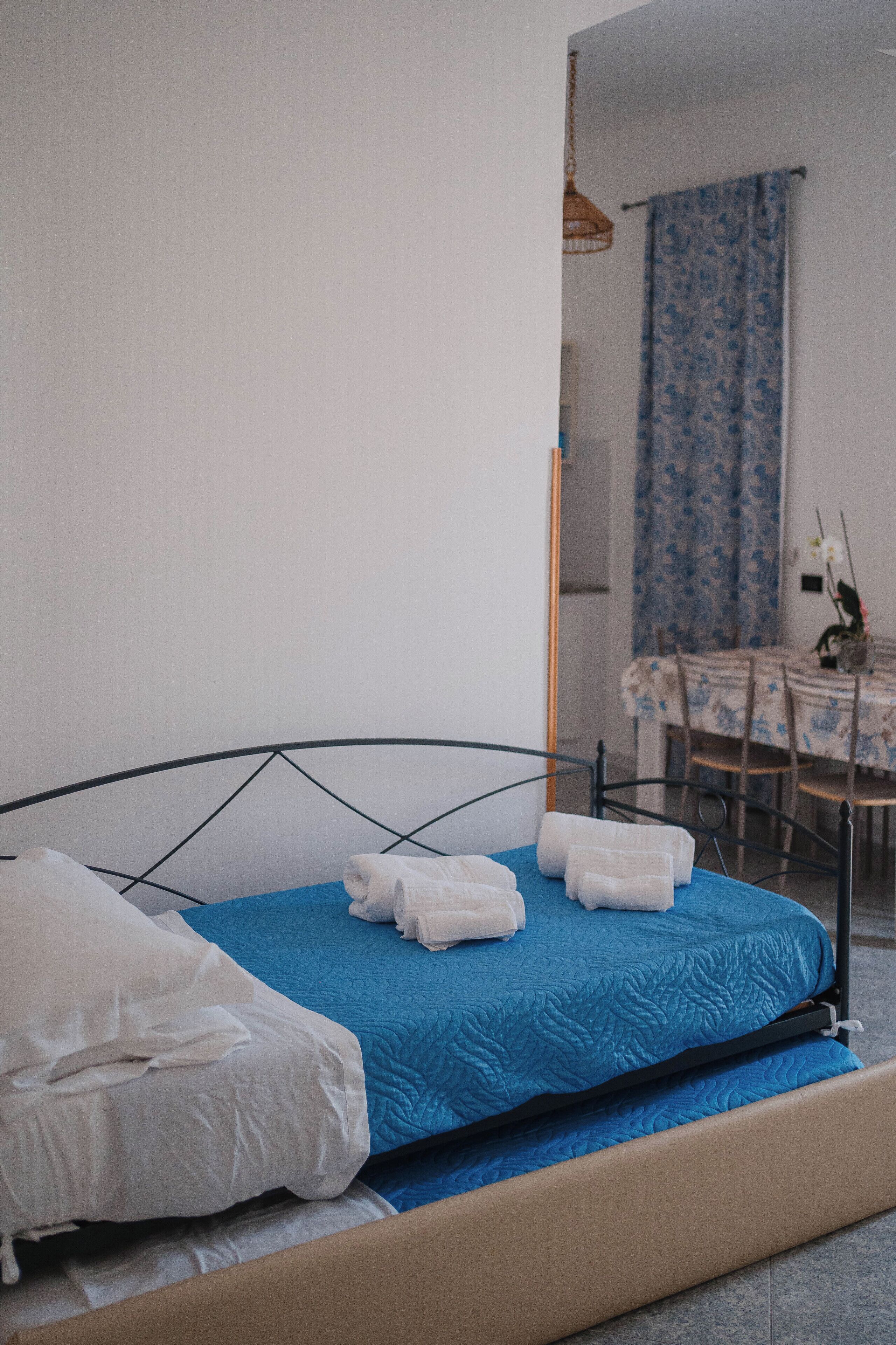 A bedroom with a bed, a table, and chairs in the background.