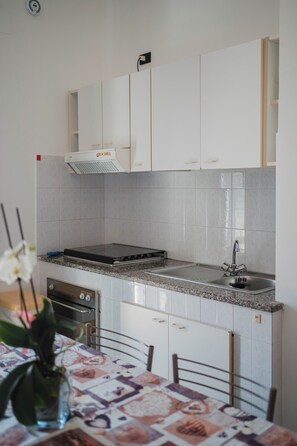 A compact kitchen with white cabinets, a stainless steel sink, and a built-in stove.