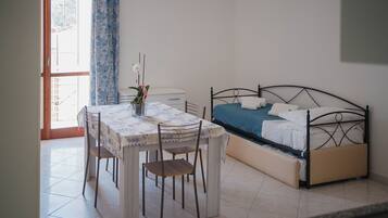 A bedroom with a bed, a bedside table, a chair, and a window with curtains.