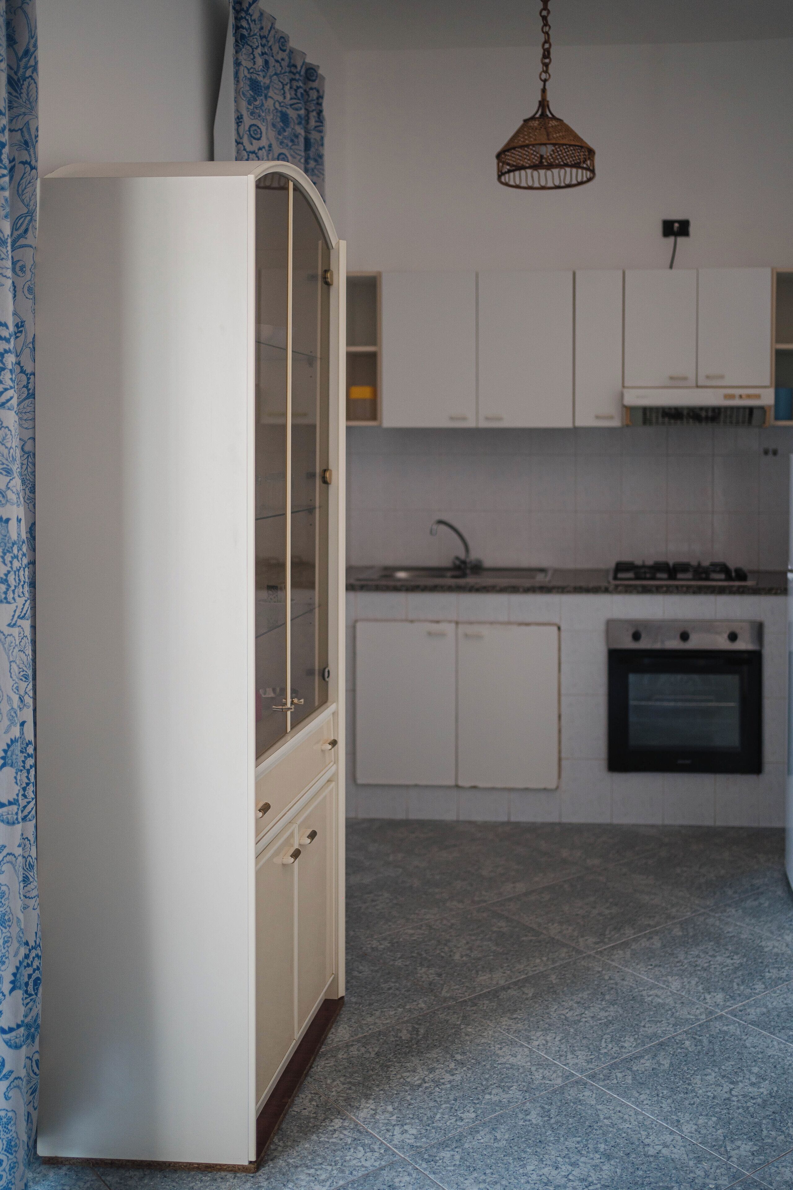 A kitchen with a white cabinet, a stove, and a sink.