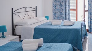 Ein Hotelzimmer mit zwei Betten, einem Nachttisch, einer Lampe und einem Fenster mit Vorhängen.