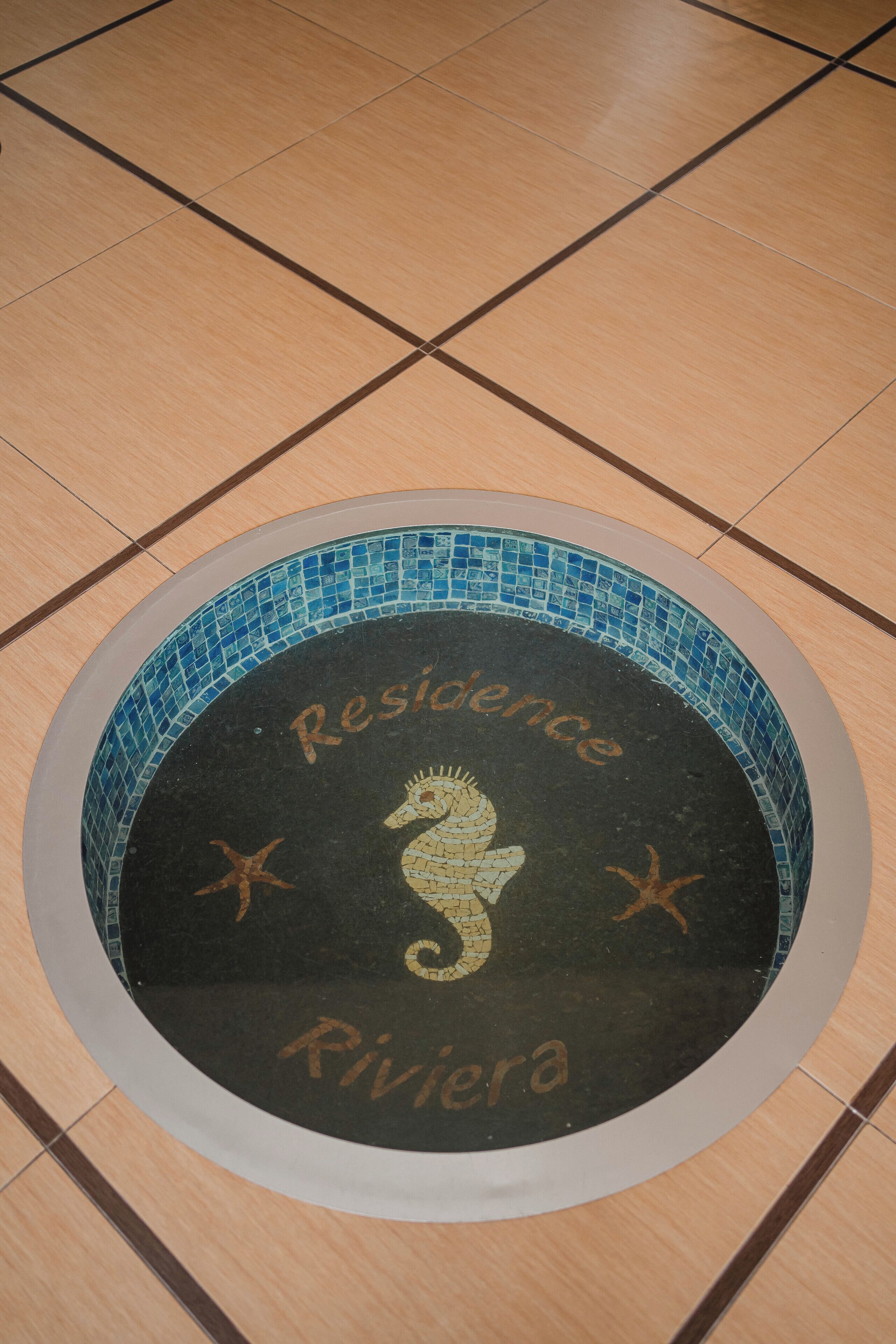 Un mosaico circular con las palabras "Residence Riviera" y un diseño de caballito de mar.