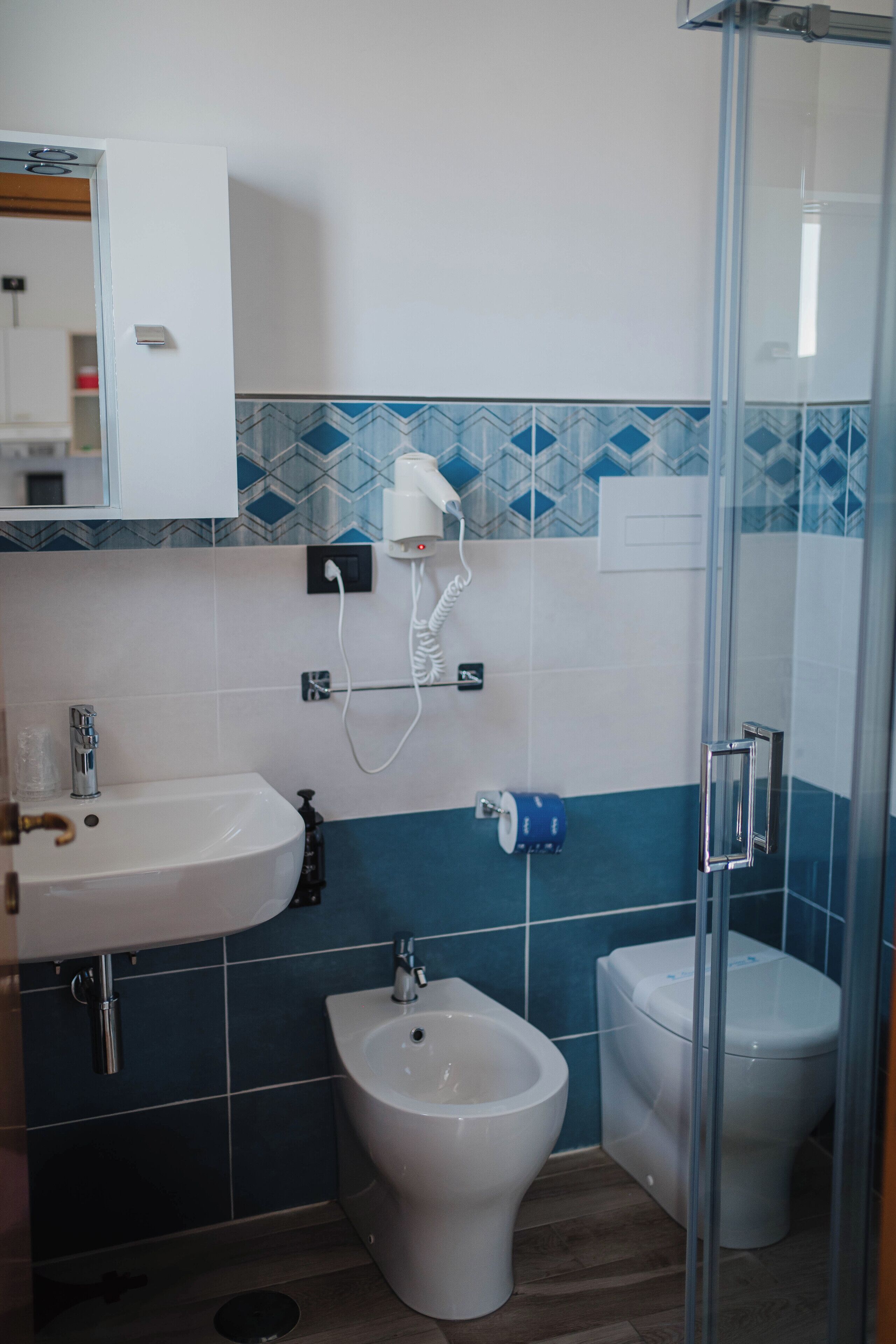 Ein Badezimmer mit Waschbecken, Bidet, Toilette und einer Duschkabine aus Glas.
