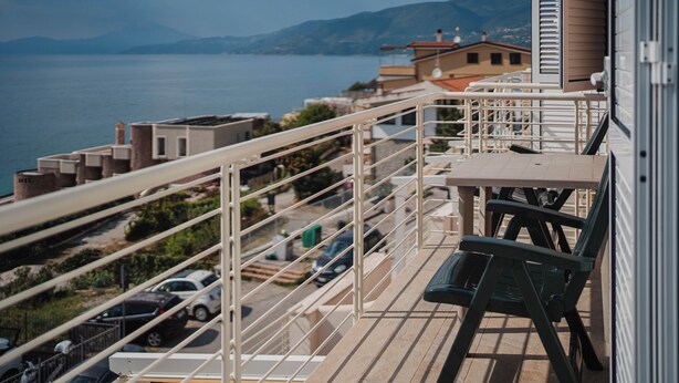 Ein Balkon mit Blick auf Meer und Berge, inklusive Tisch und Stühlen.