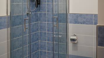 A shower with a glass door, a toilet, and blue-tiled walls.