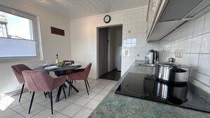 A modern kitchen with a dining area, featuring a kitchen island with a stove, a sink, and a clock on the wall.