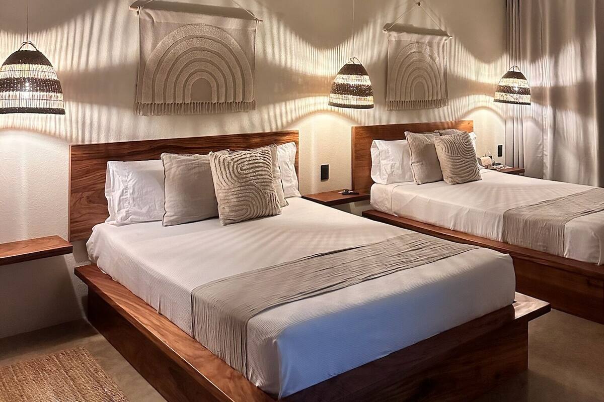 A hotel room with a large bed, two bedside tables, and a ceiling fan.
