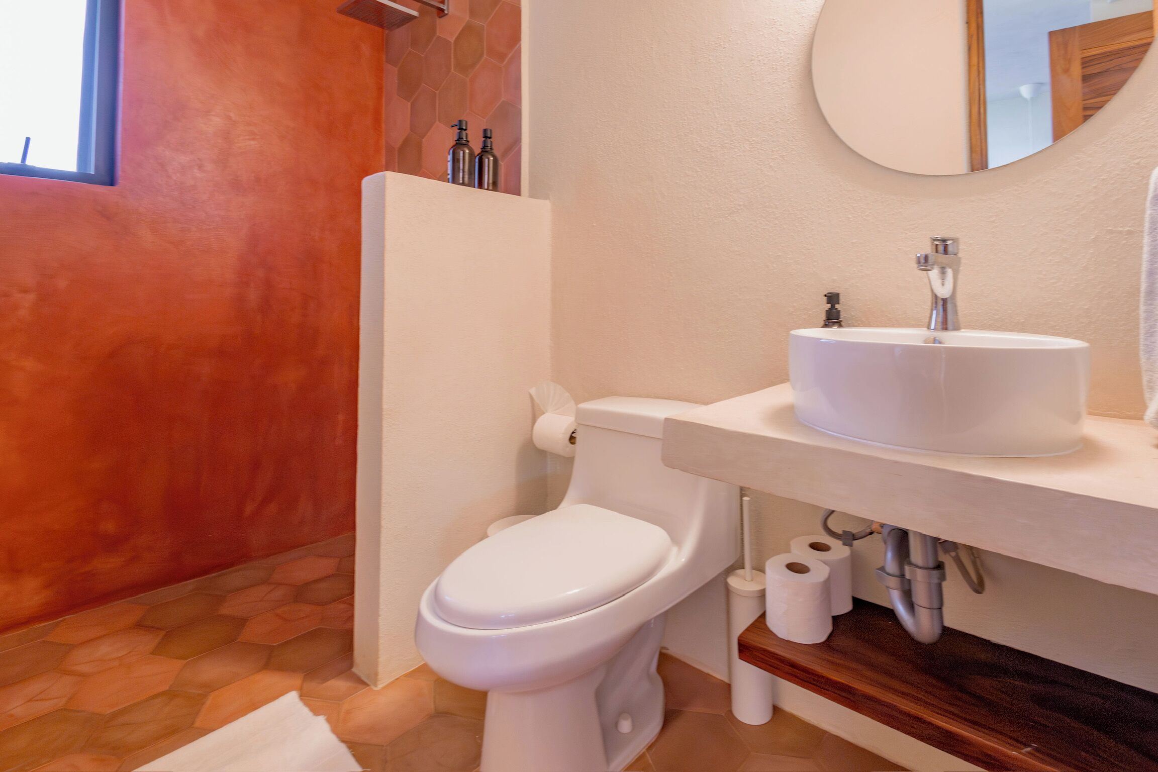 A bathroom with a white toilet, a round sink, and a mirror above it.