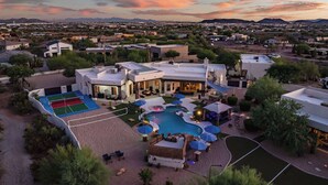 Un resort con piscina, mobiliario exterior y cancha de tenis.