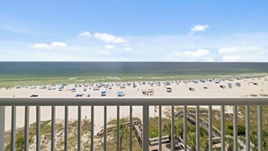 A beach with umbrellas and people, a wooden boardwalk, and a clear sky. - Tradewinds 605 by Liquid Life (Orange Beach)