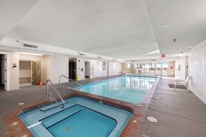En inomhuspool med tydligt markerade banor, en livräddarstol och ett omklädningsrum i bakgrunden.