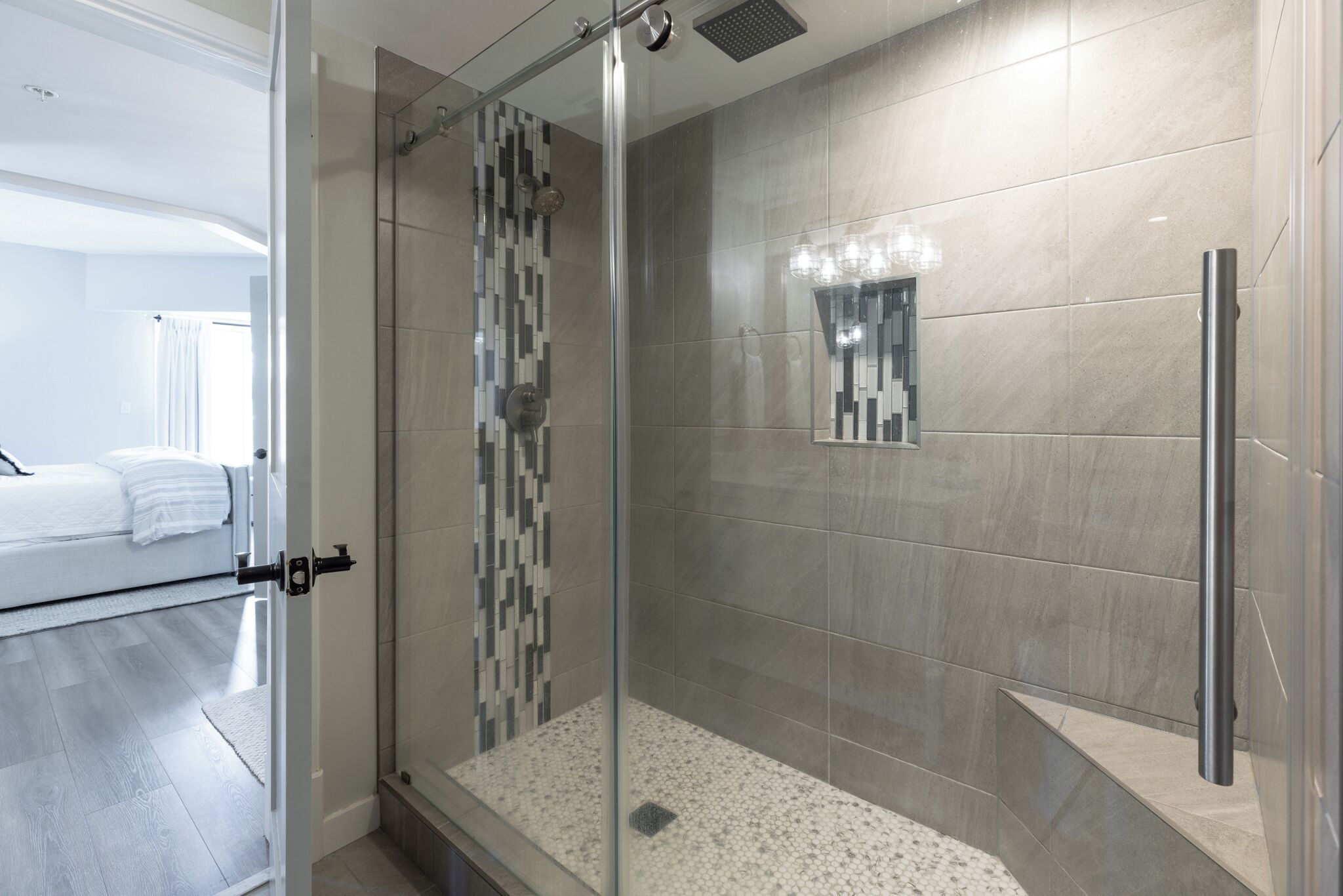 A modern bathroom with a glass-enclosed shower, a tiled floor, and a small mirror on the wall.