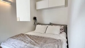 Une chambre à coucher comprenant un lit, une table de chevet, un miroir et un meuble fixé au mur.