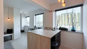 Une cuisine moderne dotée d’un îlot central, de grandes fenêtres et offrant une vue sur les bâtiments environnants.