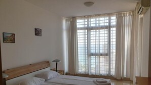Ein Hotelzimmer mit zwei Betten, einem Nachttisch, einer Lampe und einem Fenster mit Vorhängen.