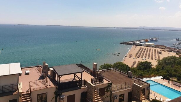 Blick auf die Küste mit Strand, einer Mole und einem Schwimmbad.